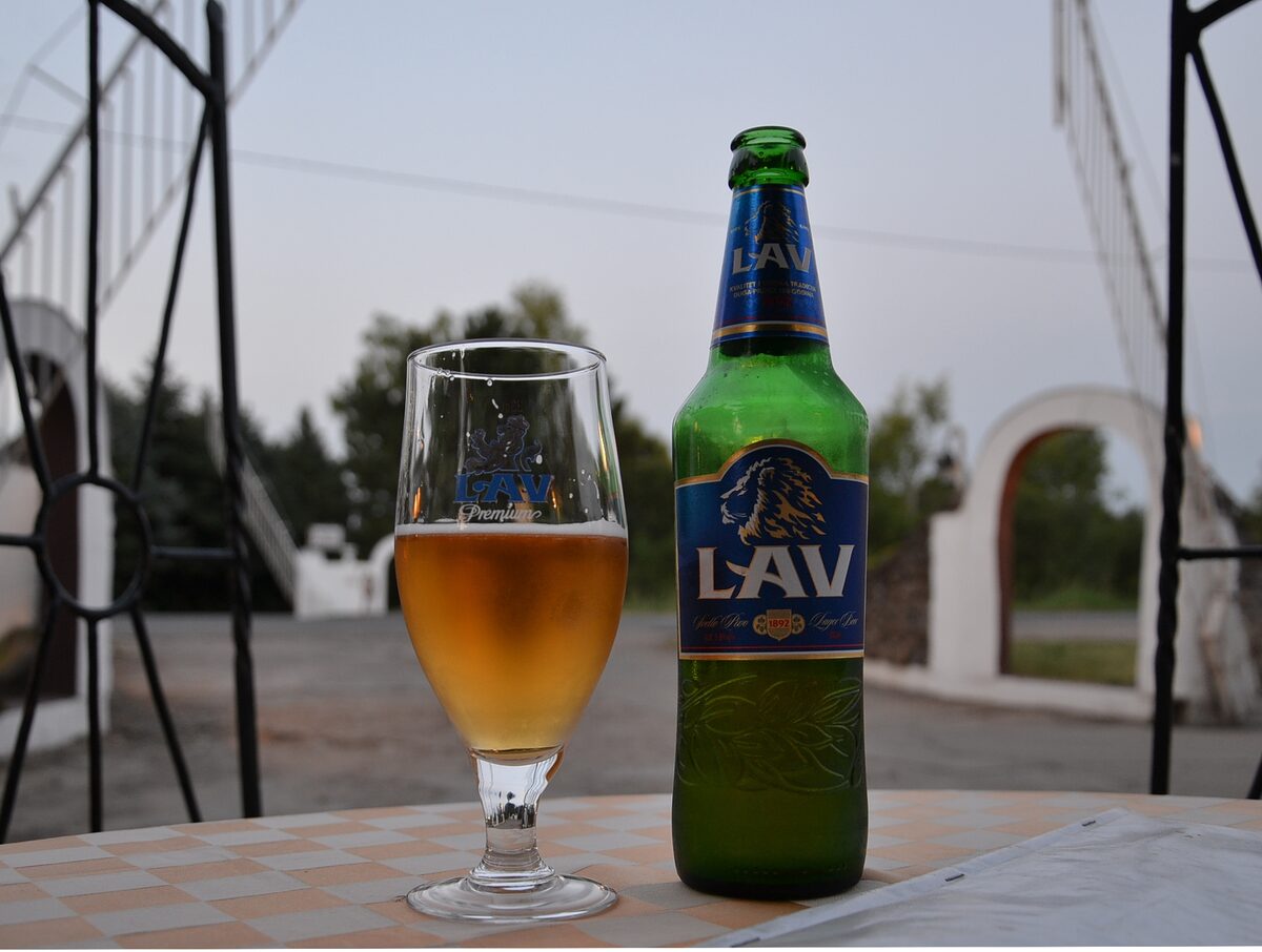 A glass and a green bottle of Lav lager on a table in Serbia