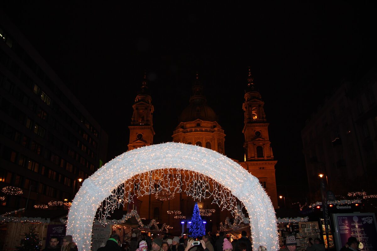 A glowing arch of lights at the Christmas market in front of St. Stephen's Basilica in Budapest at night