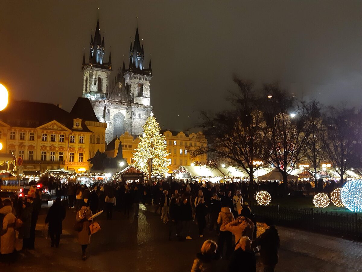 Crowds, stalls and the lit tree on Old Town Square in Prague, with the Tyn Church behind