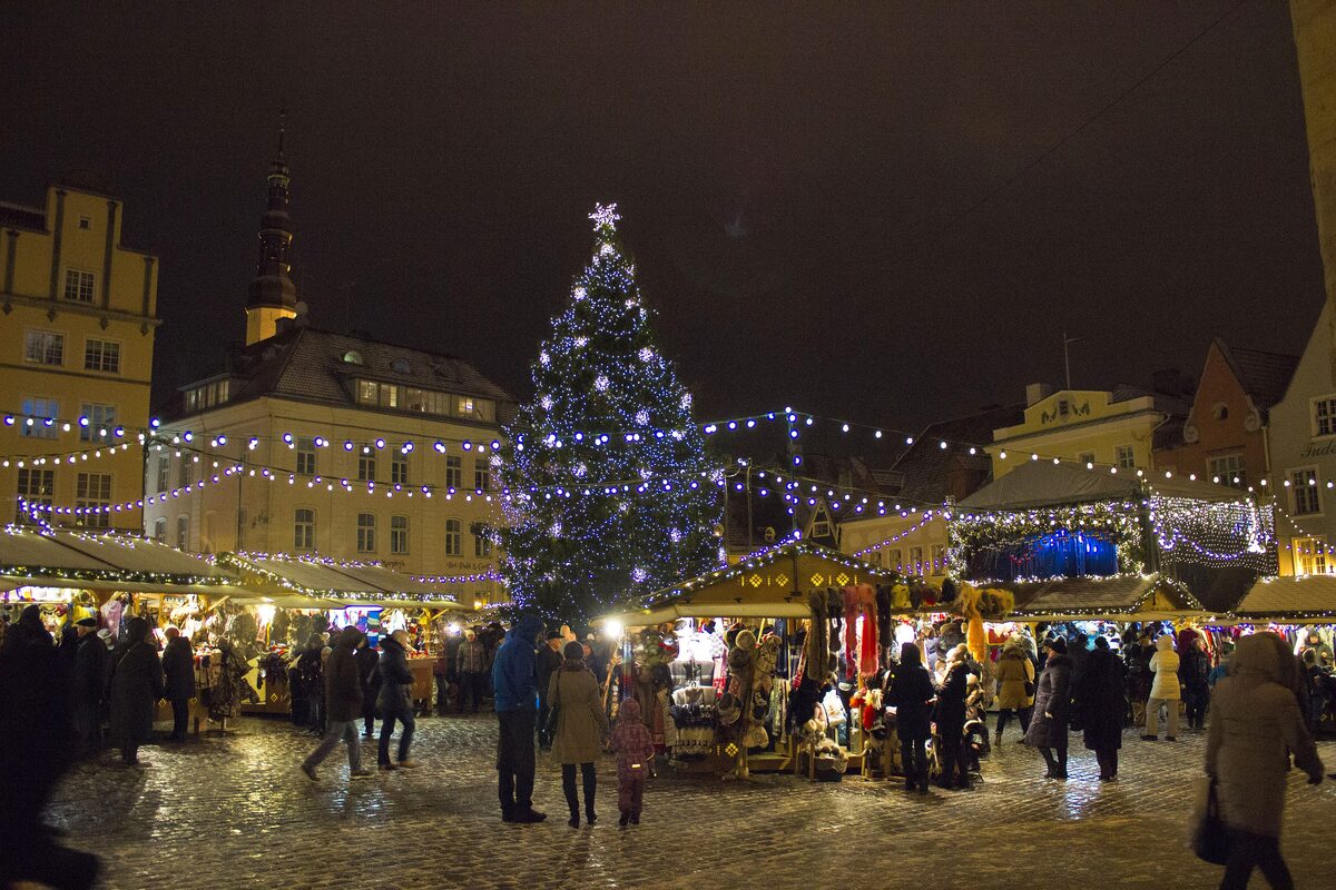 The lit Christmas tree and market stalls on Town Hall Square in Tallinn at dusk