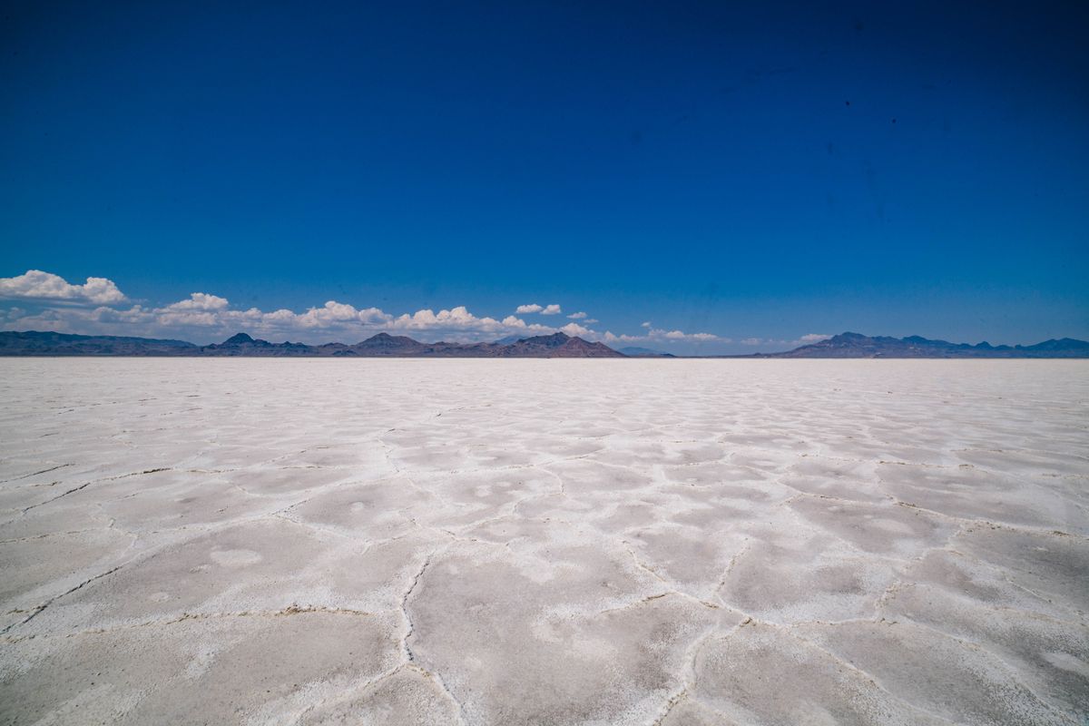 The white, perfectly flat surface of the Bonneville Salt Flats in Utah with mountains on the horizon