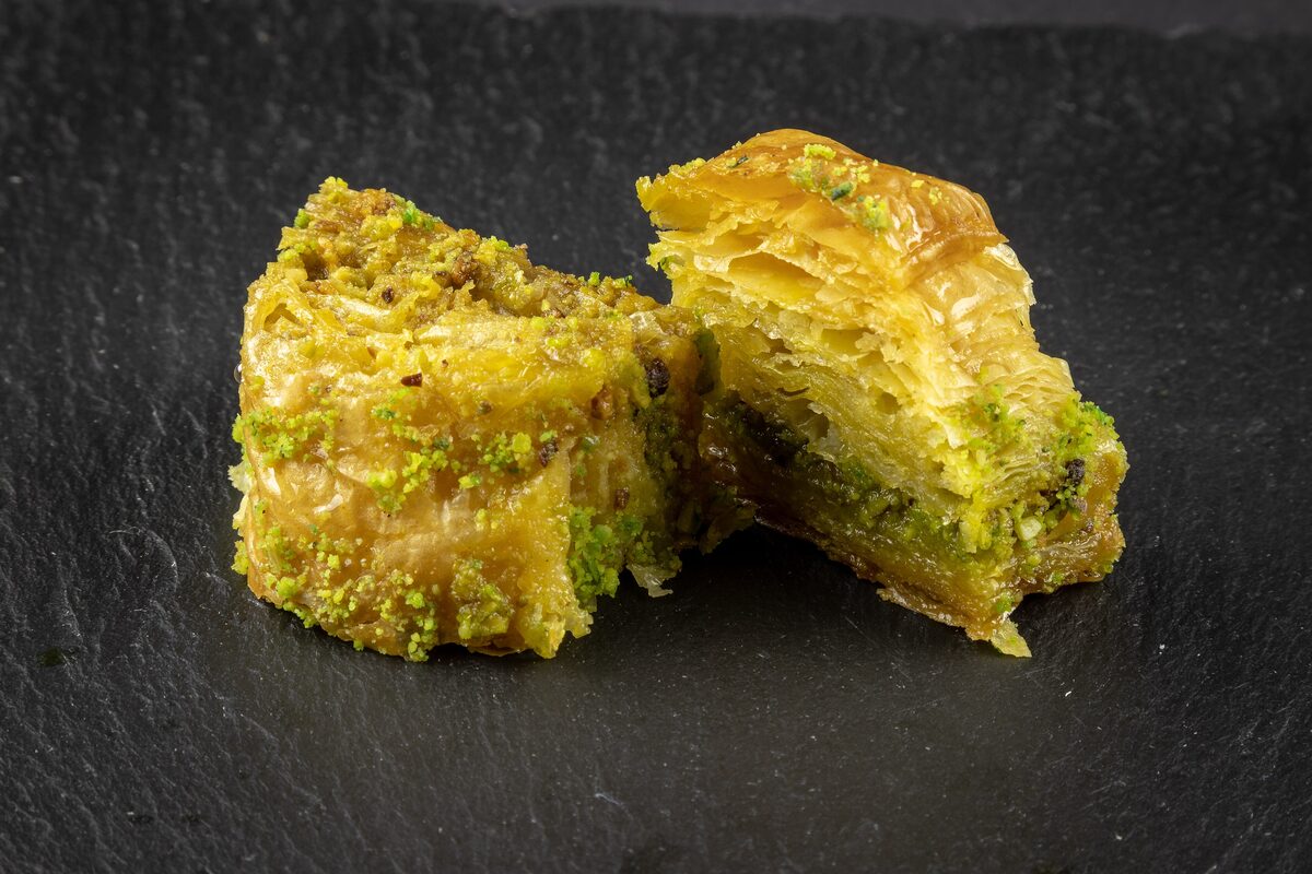 Two pieces of Turkish pistachio baklava, one cut open to show the green filling and thin layers