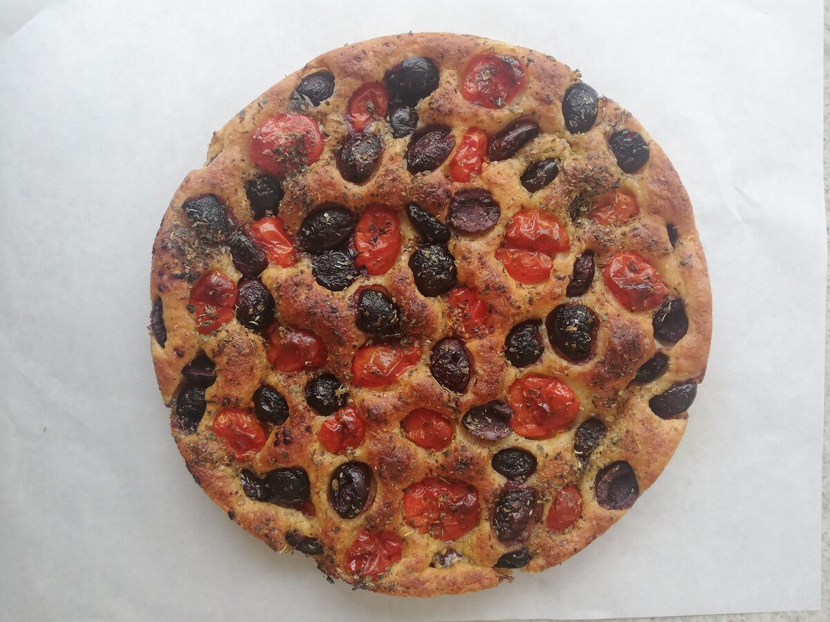 A round Barese focaccia topped with cherry tomatoes and black olives
