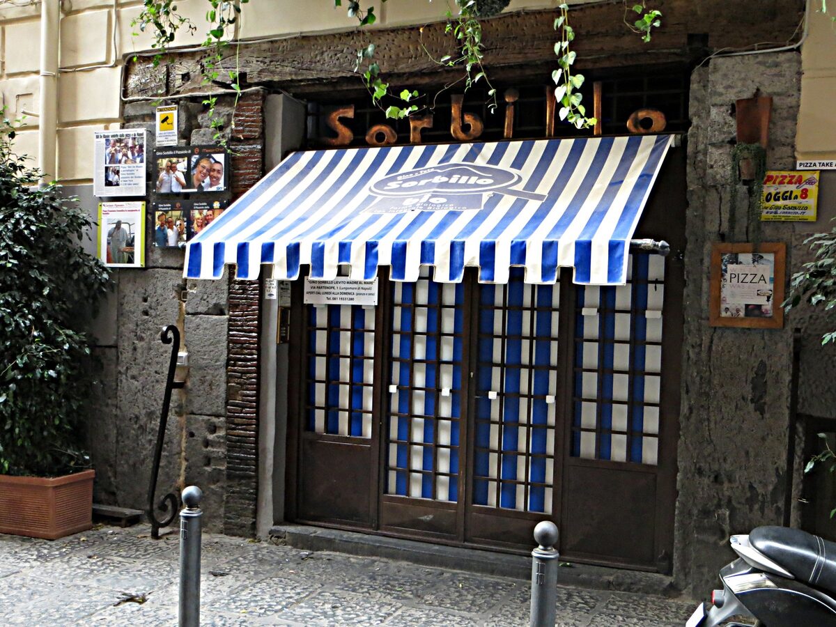 The blue-and-white striped awning of Pizzeria Gino Sorbillo on Via dei Tribunali in Naples
