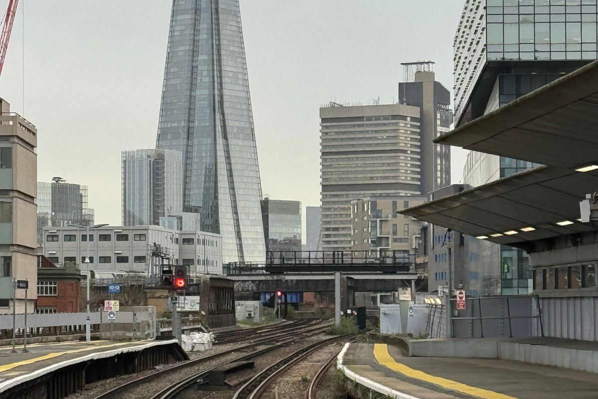 Railway tracks curving into London past Waterloo East station platforms, with the Shard rising above the city