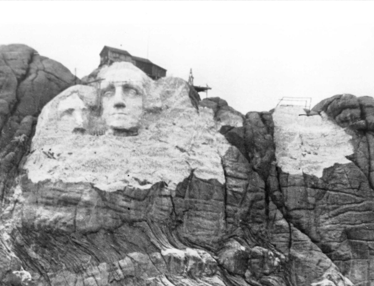 Mount Rushmore during carving in the late 1930s, with Washington finished and the abandoned Jefferson to his left