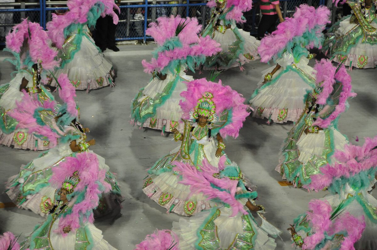 Dancers in pink and green feathered costumes seen from above on the Sambadrome avenue in Rio