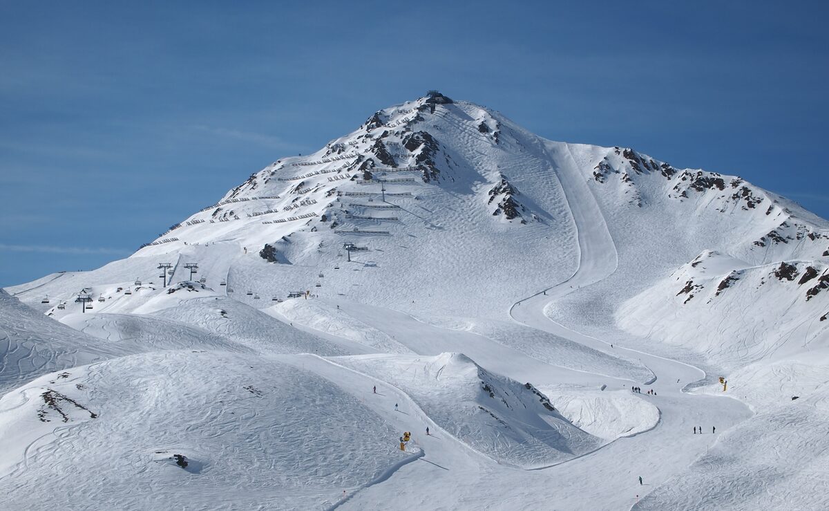 A broad groomed slope with a chairlift at Serfaus-Fiss-Ladis below a snowy summit