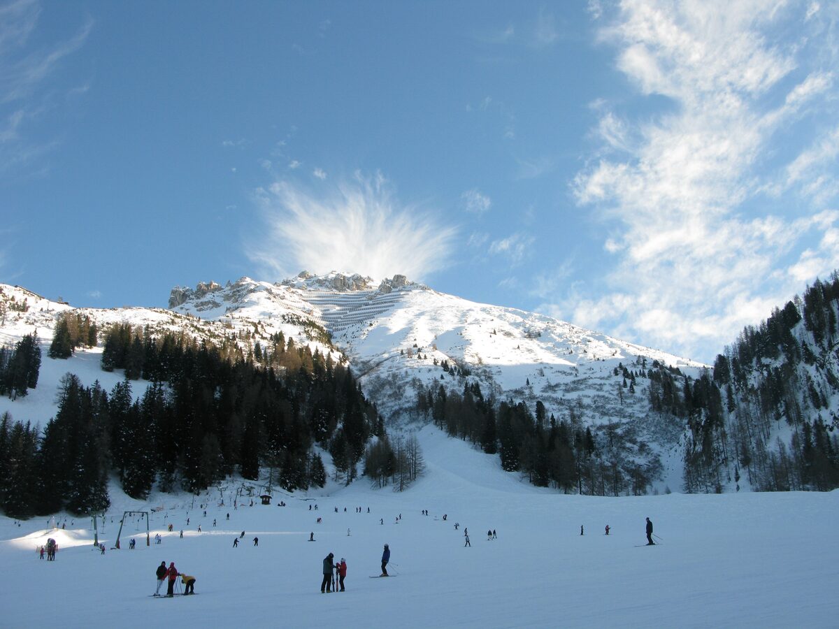 Skiers on a gentle slope at Axamer Lizum near Innsbruck with a snowy mountain behind
