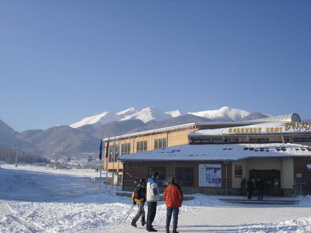 The Bansko gondola base station on a sunny day, with the snowy Pirin mountains behind