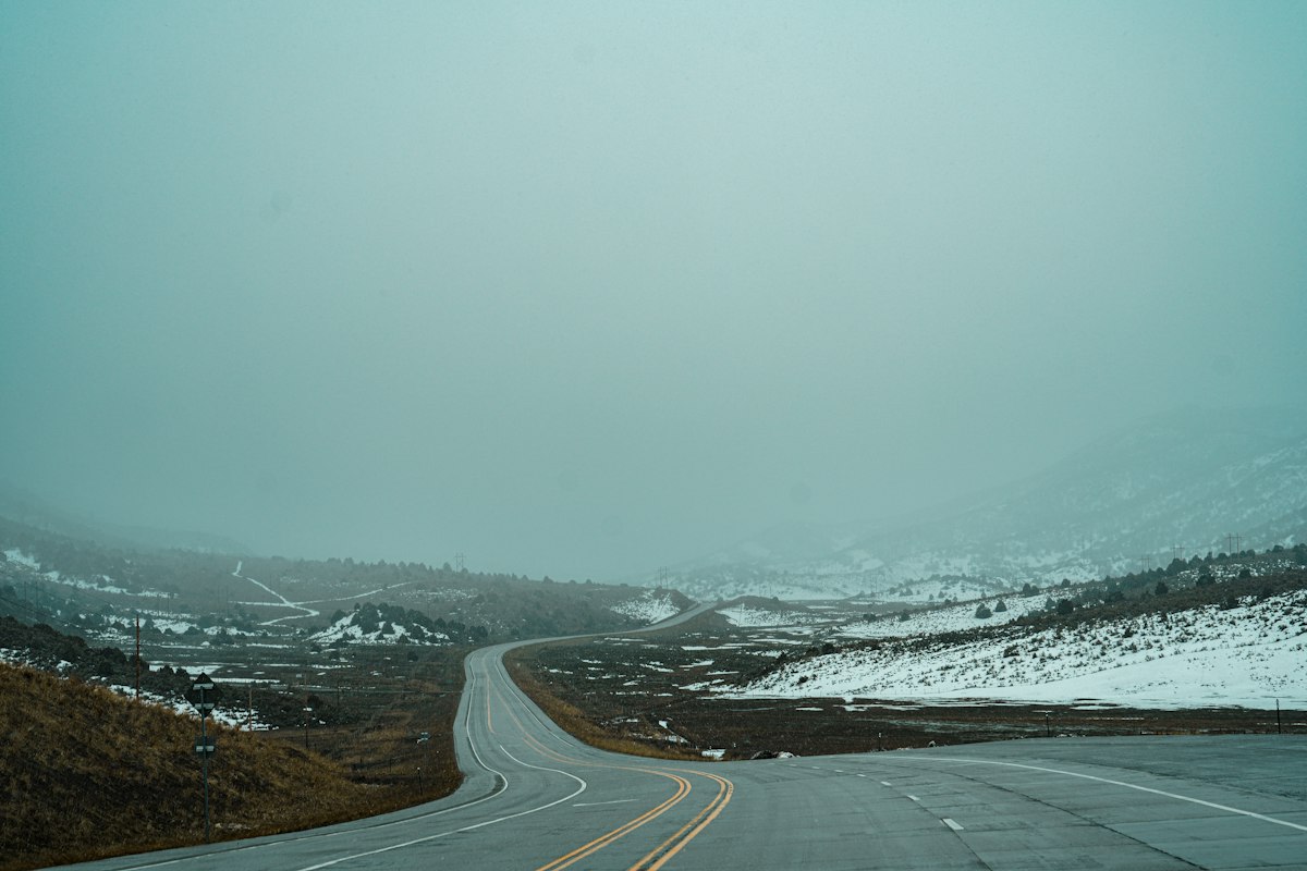 Empty highway curving through snowy, foggy hills in Wyoming in winter