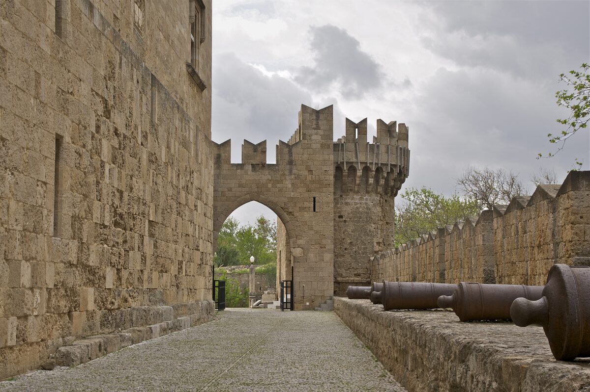 A gate, towers and old cannons along the stone walls of the medieval Old Town of Rhodes