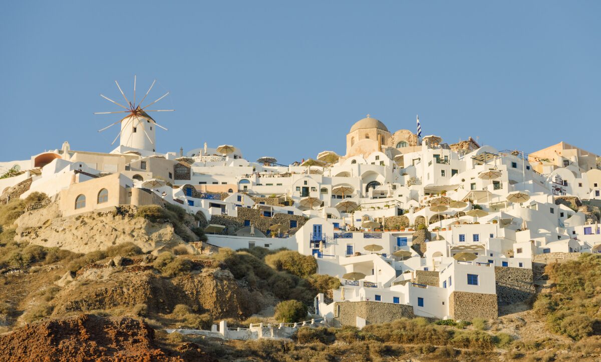 White houses and a windmill on the cliff at Oia on Santorini under a blue sky