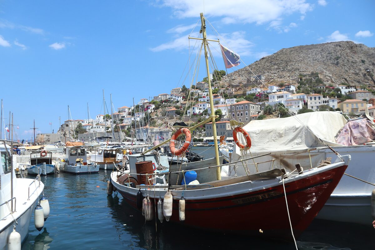 A wooden fishing boat in the small harbour of Hydra, with white houses climbing the hillside behind