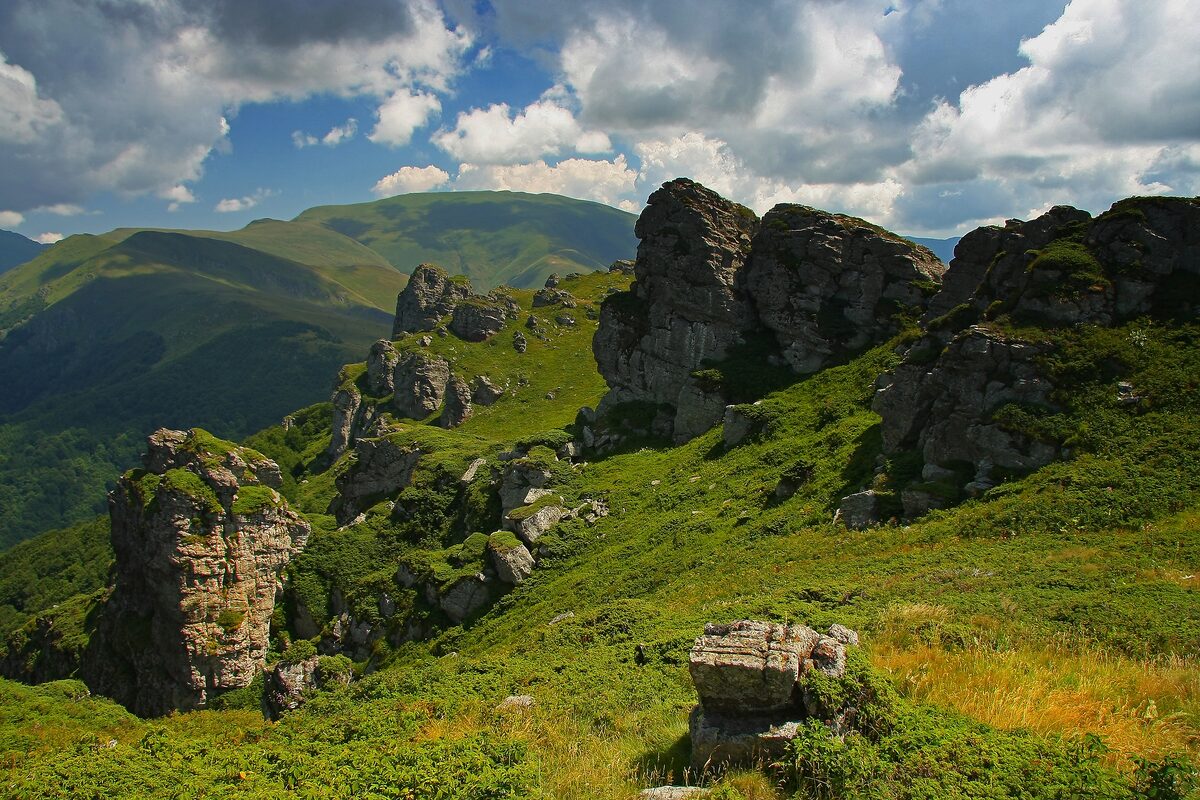 Stara planina in summer: green ridges and weathered rock towers near Babin zub under a cloudy sky