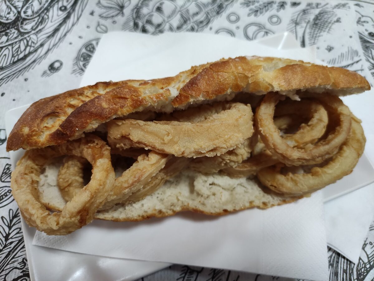 A bocadillo de calamares, a crusty roll filled with fried squid rings, on a paper napkin