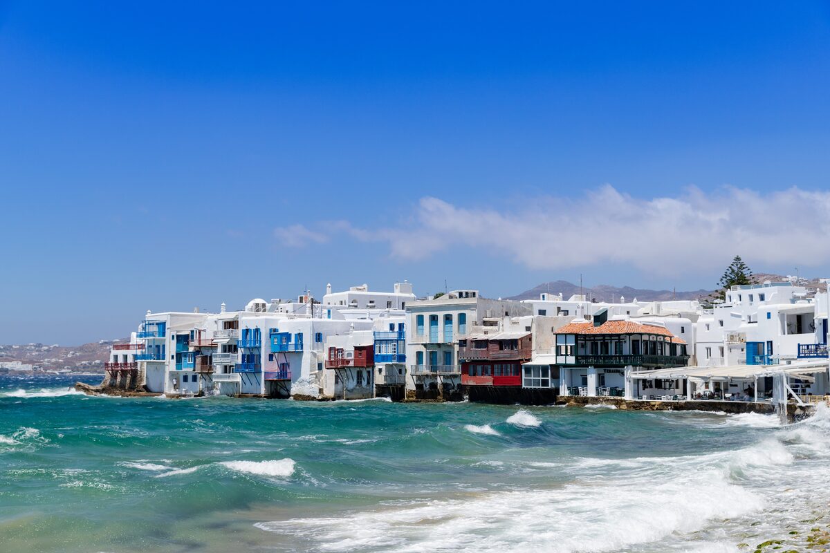White houses with blue and red balconies over the waves at Little Venice in Mykonos Town