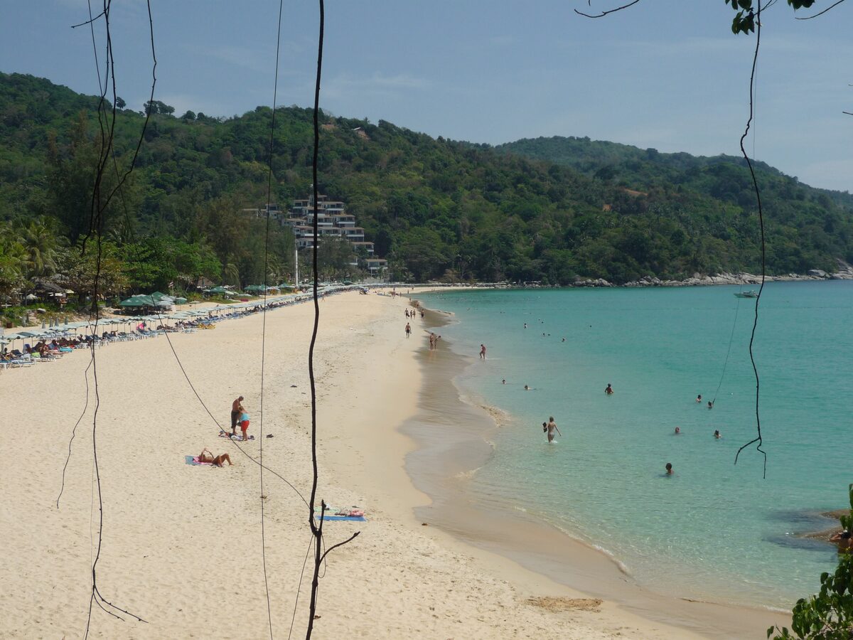 Kata Noi beach on Phuket seen from above: pale sand, sunbeds and turquoise water below forested hills