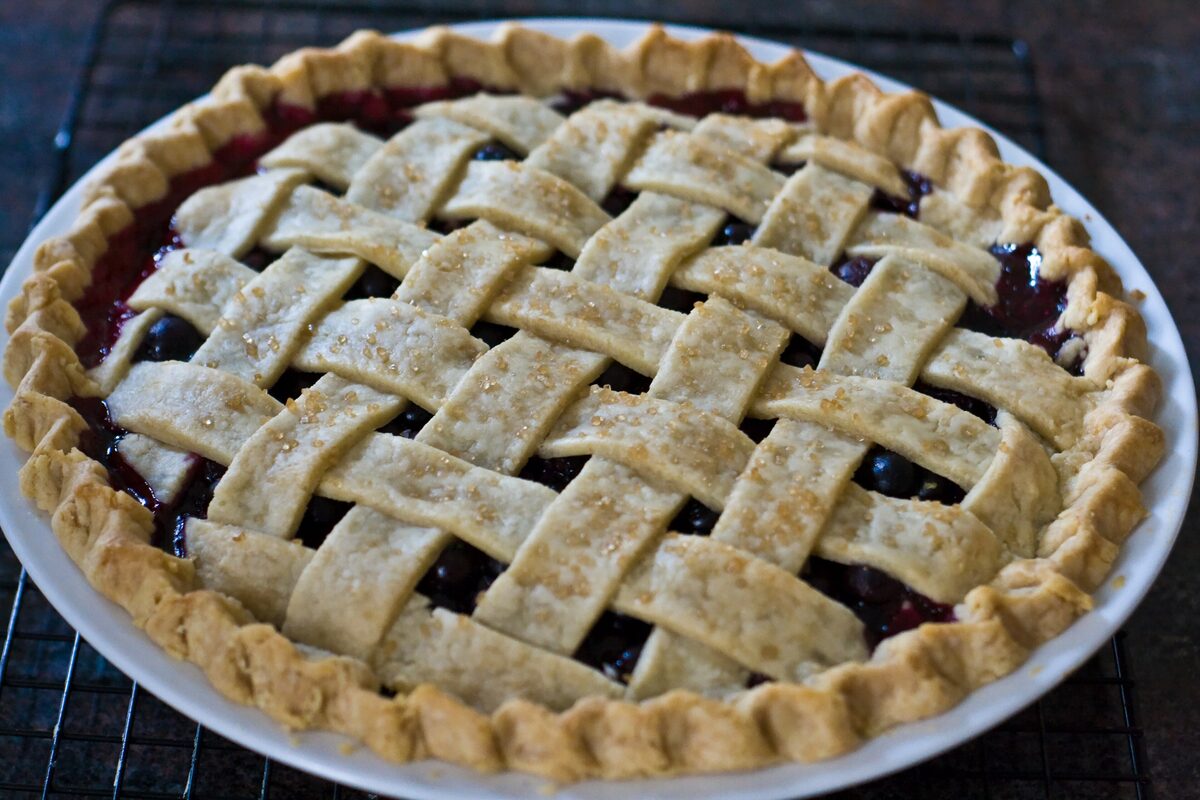 A lattice-topped blueberry pie cooling on a wire rack