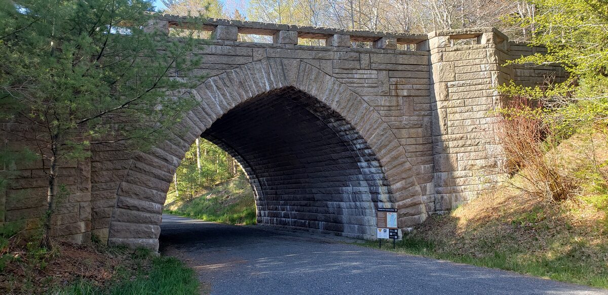 A granite arch carriage road bridge crossing a paved road