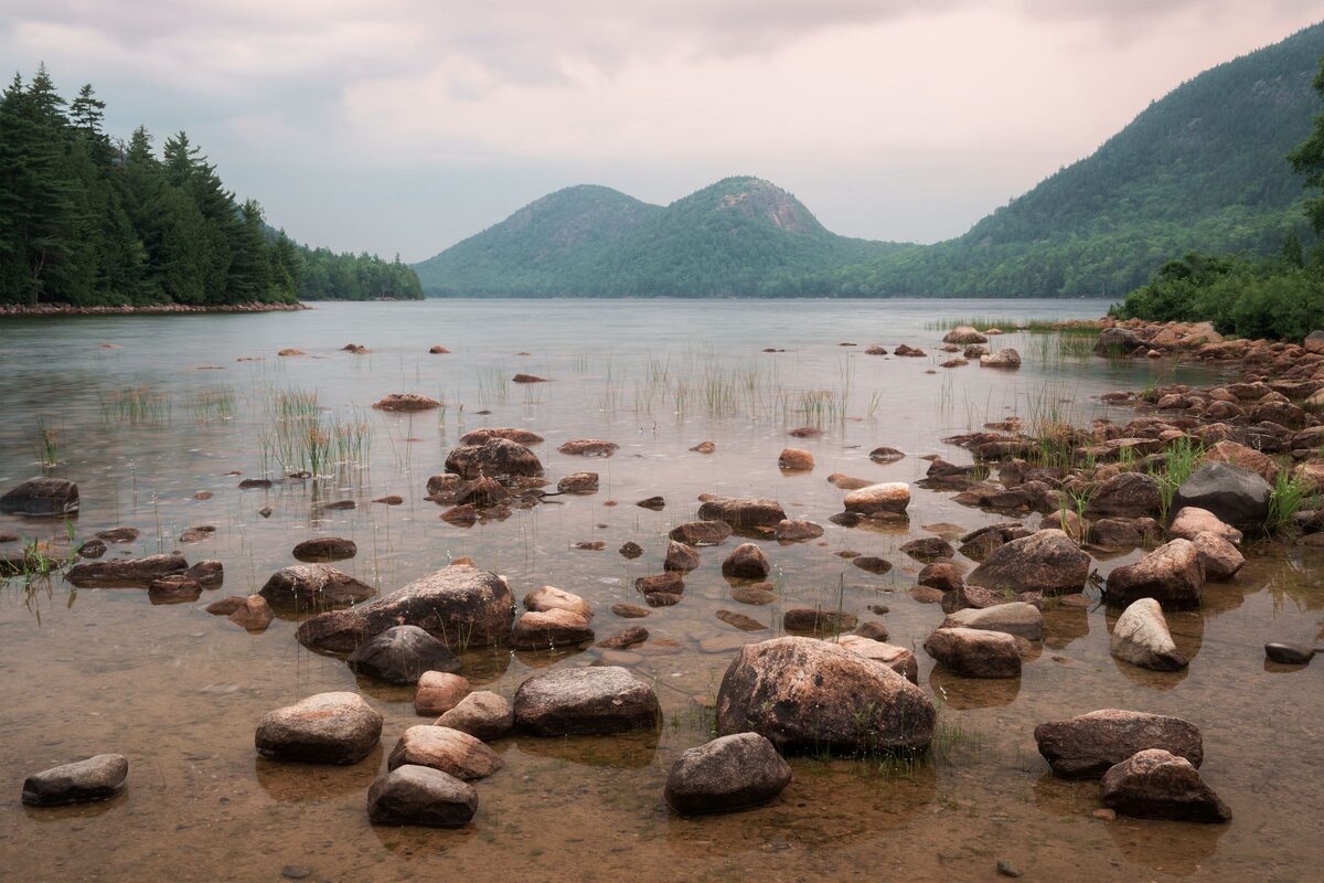 Jordan Pond with boulders in the shallows and the Bubbles beyond