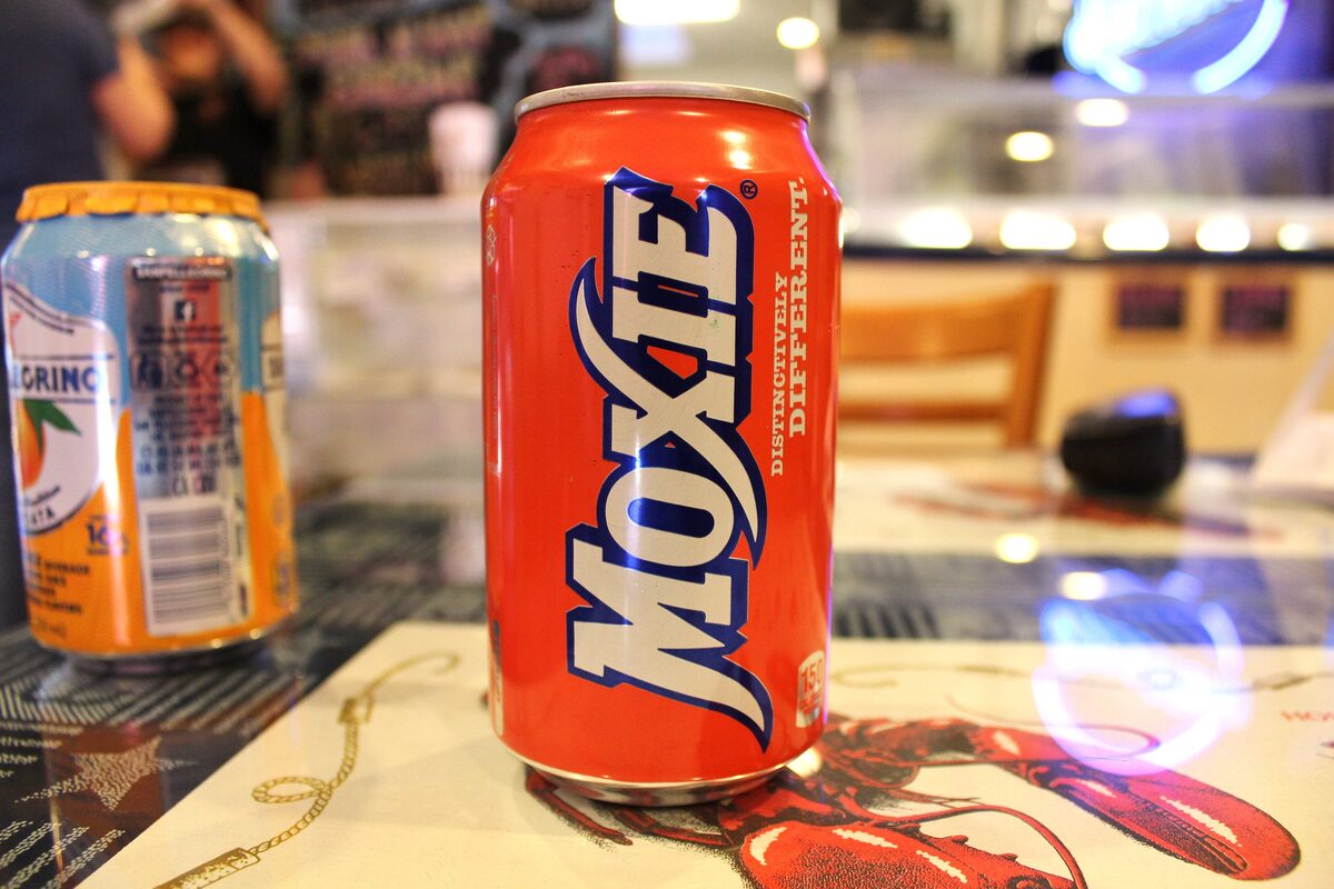 A red can of Moxie soda standing on a diner table