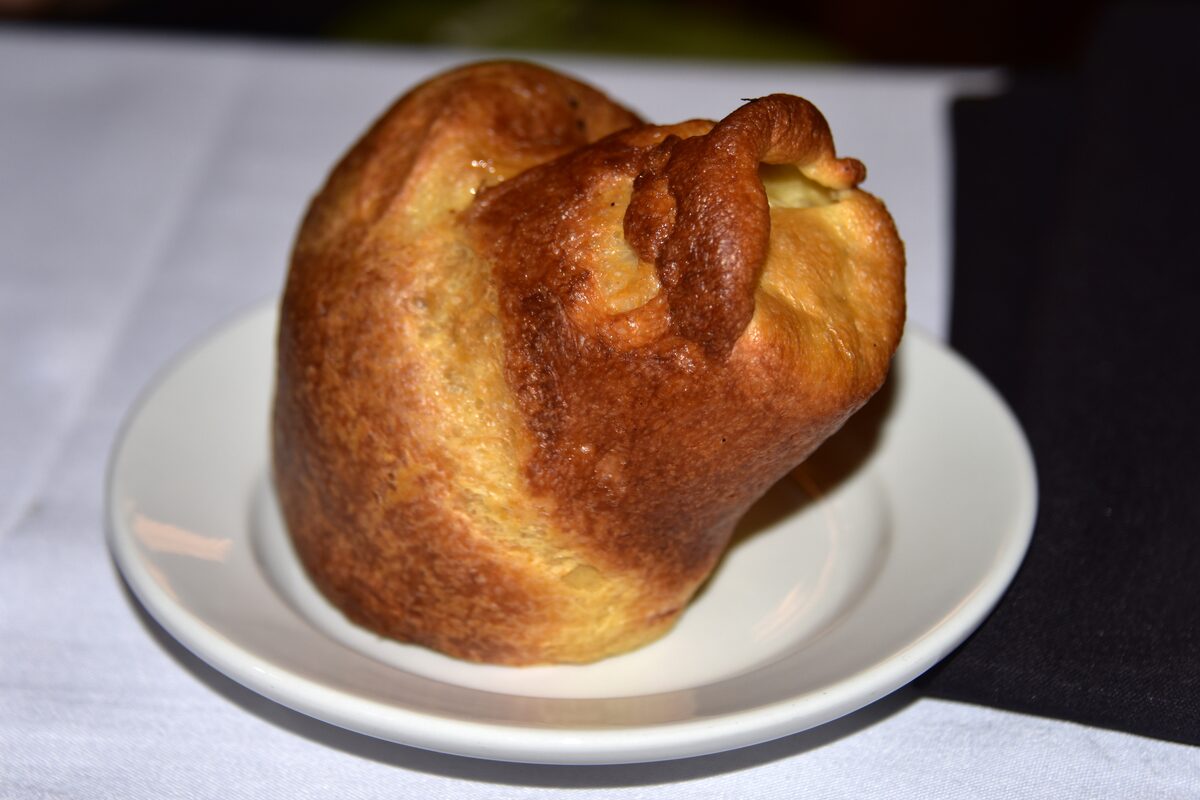 A tall golden brown popover served on a white plate