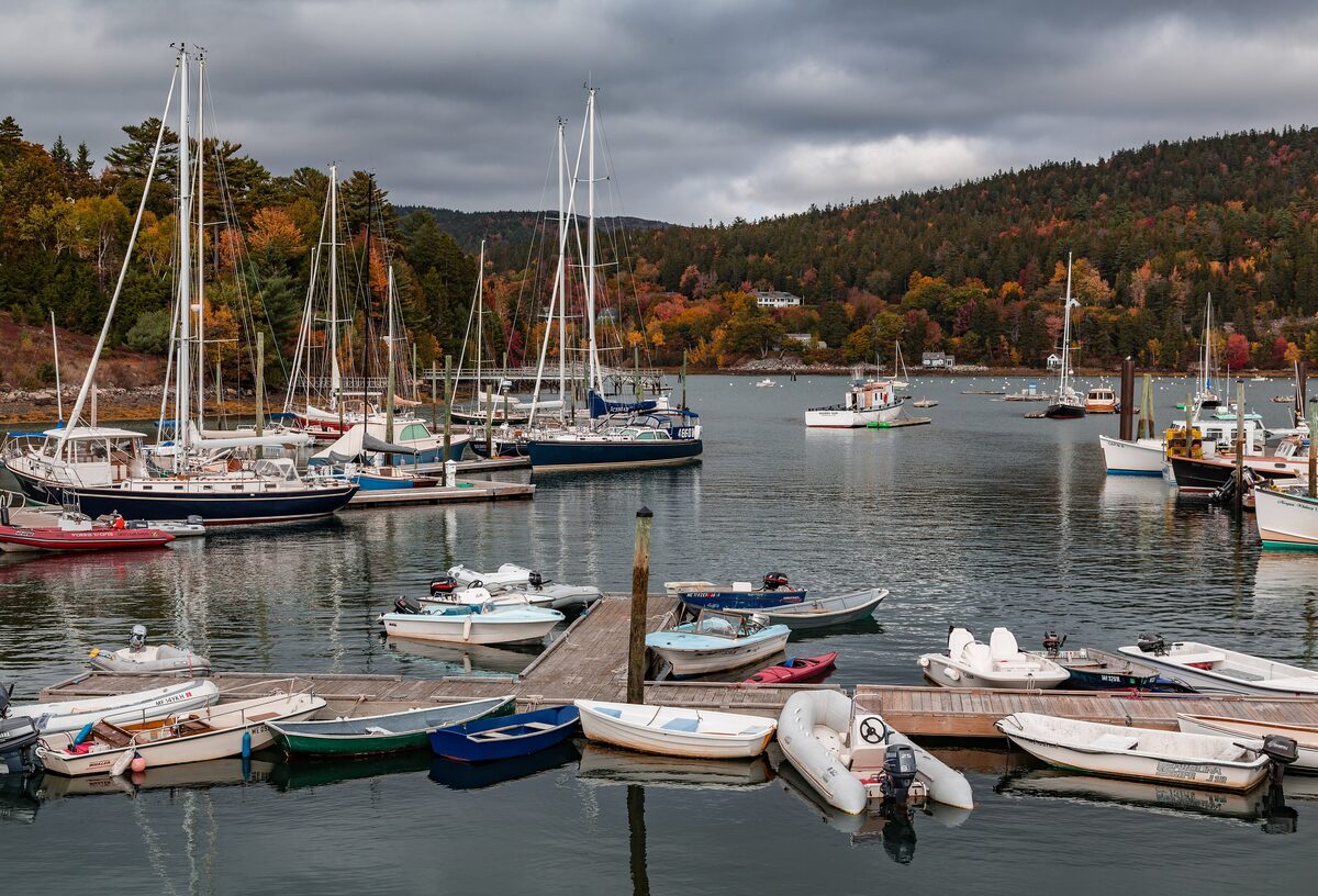 Sailboats and small dinghies moored in Northeast Harbor under autumn hills