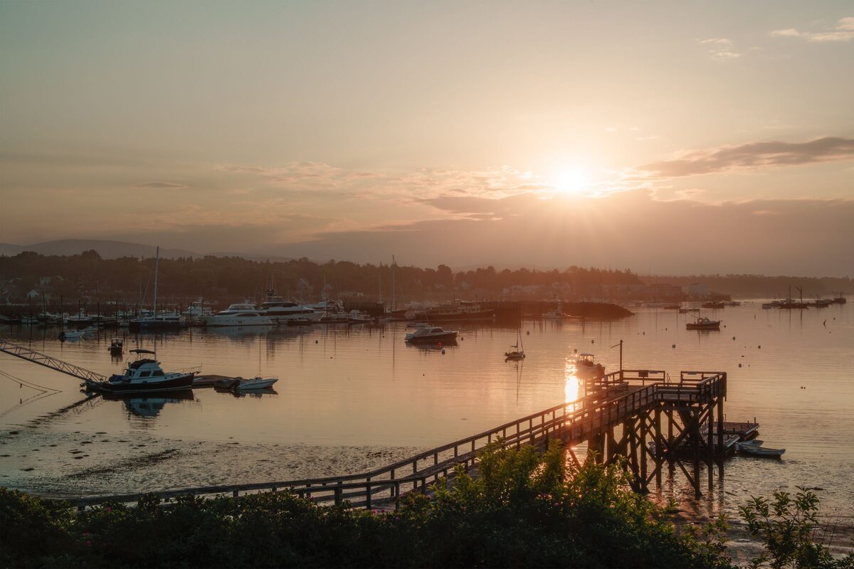 Sunrise over the Southwest Harbor waterfront with a wooden pier and moored boats