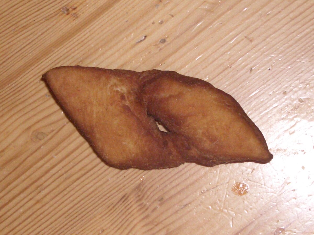 A kleina, a flat deep-fried pastry on a wooden table