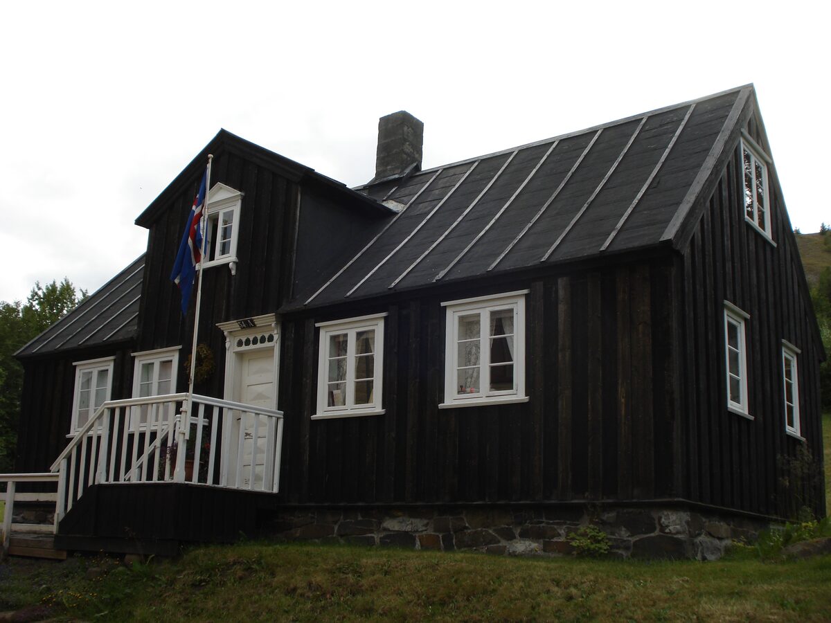 Nonnahús, a small black timber house with white window frames and a flagpole in Innbærinn
