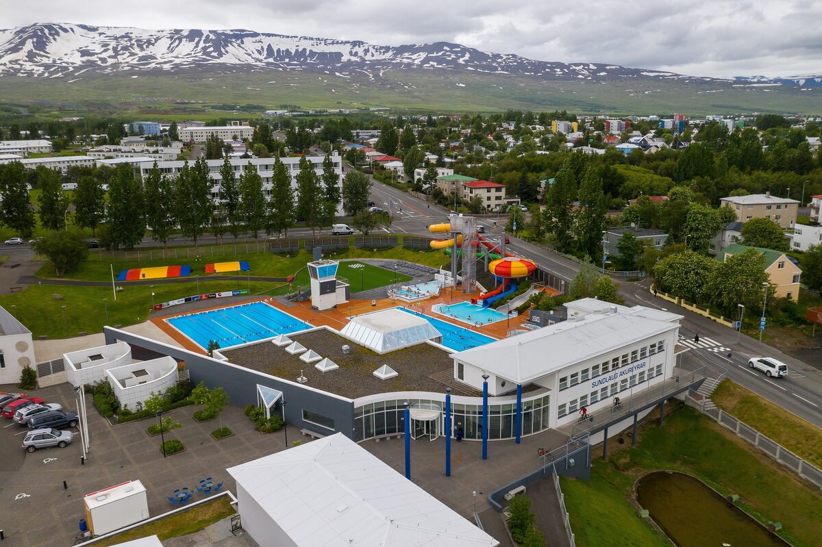 Aerial view of the Akureyri town pool, with its outdoor basins and water slide beside the car park and the town
