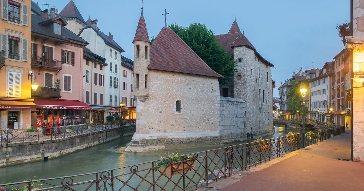 The Palais de l'Isle in Annecy, a stone house on an island in the Thiou canal with colorful houses along the water