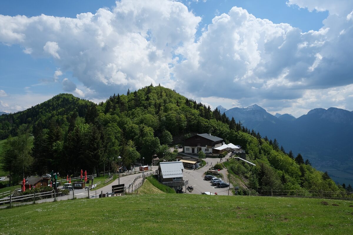The Col de la Forclaz on a grassy slope, with a restaurant and car park beside the road and mountains beyond