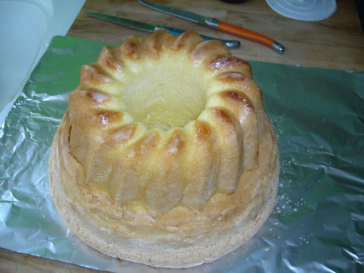 A Gâteau de Savoie, a golden sponge cake with a ridged ring shape, on a sheet of foil