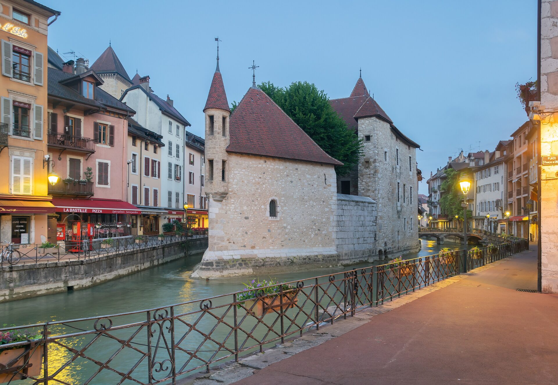 The Palais de l'Isle in Annecy, a stone house on an island in the Thiou canal with colorful houses along the water