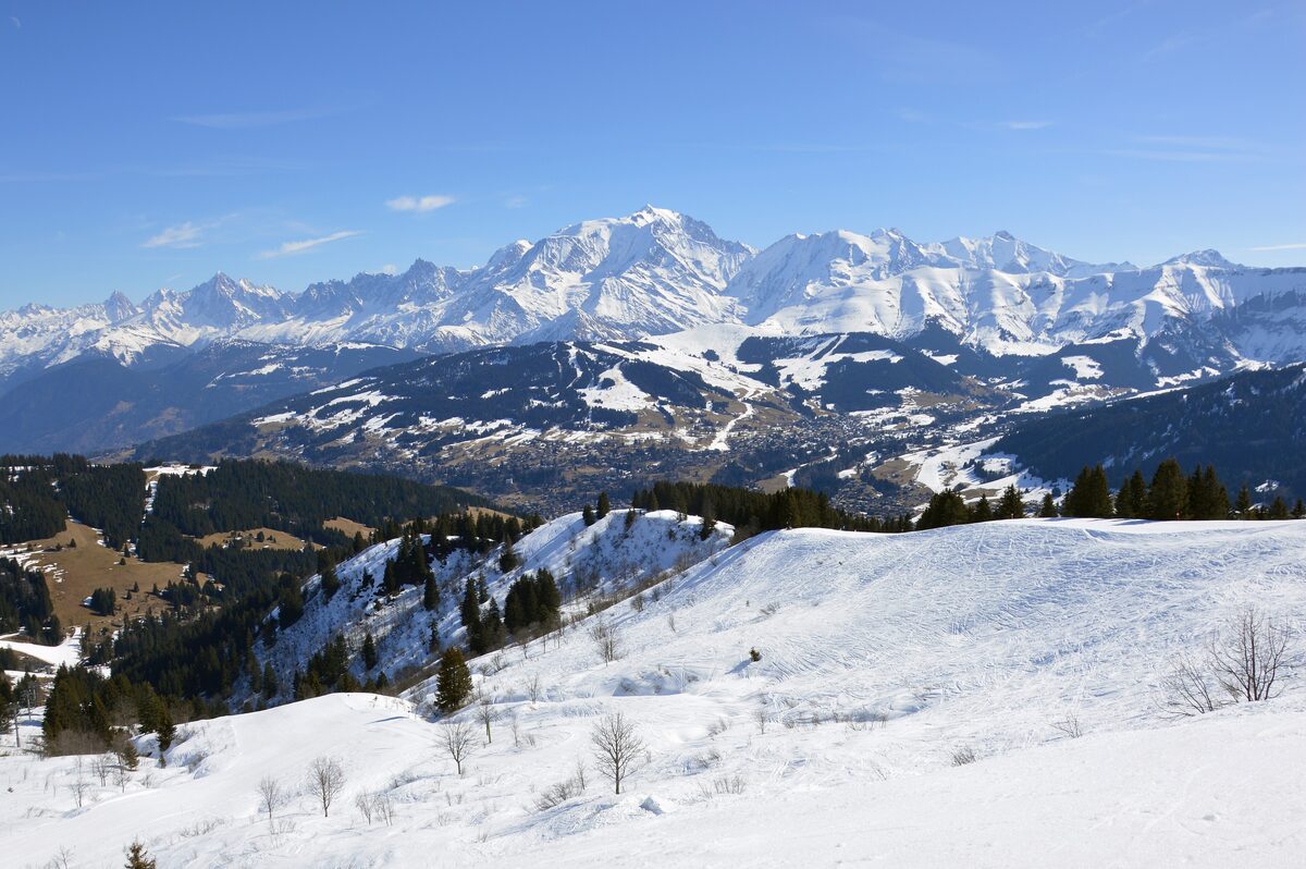The snowy slopes above Megève with a row of white peaks of the Mont Blanc massif across the horizon under a clear sky