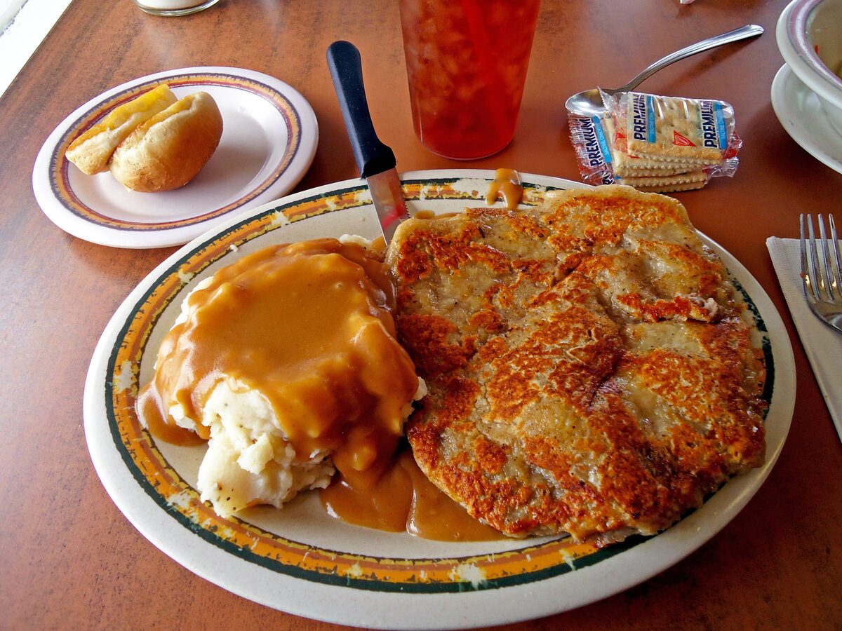 A diner plate of chicken-fried steak with mashed potatoes and cream gravy