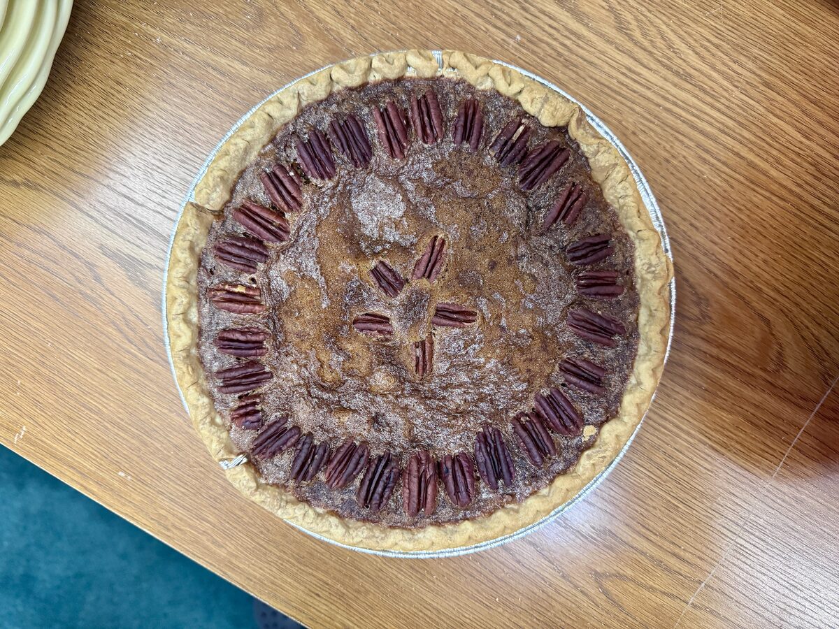 A whole pecan pie in its tin with a ring of pecan halves on top