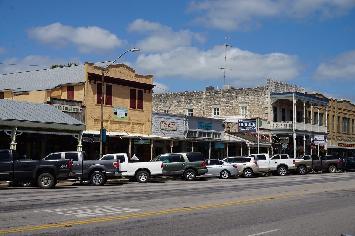 Stone and wood storefronts with deep porches along East Main Street in Fredericksburg under a blue sky