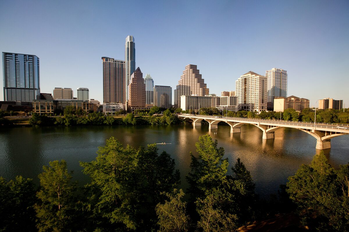 Lady Bird Lake in the evening with a road bridge and the downtown Austin skyline behind it