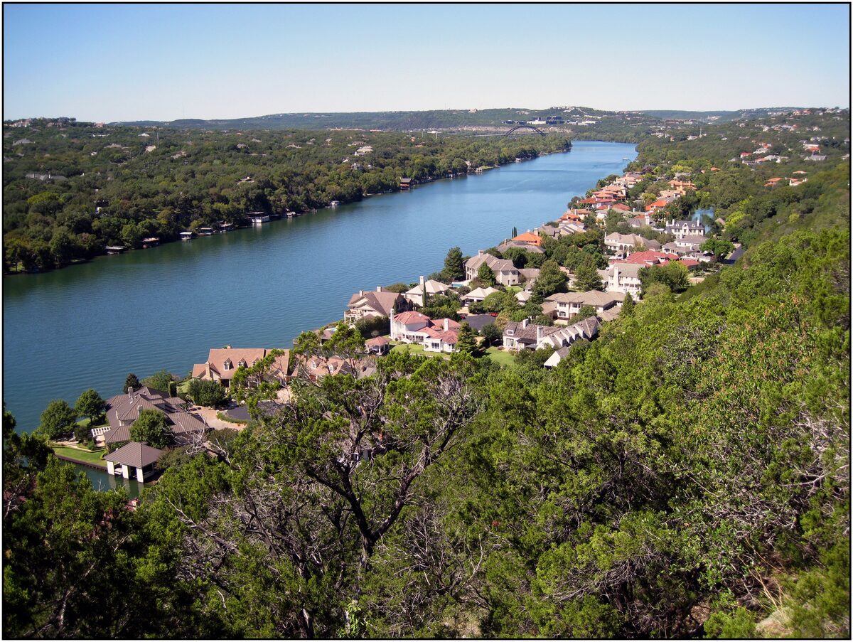 The Colorado River as Lake Austin bending away below the Mount Bonnell lookout, with houses on the shore