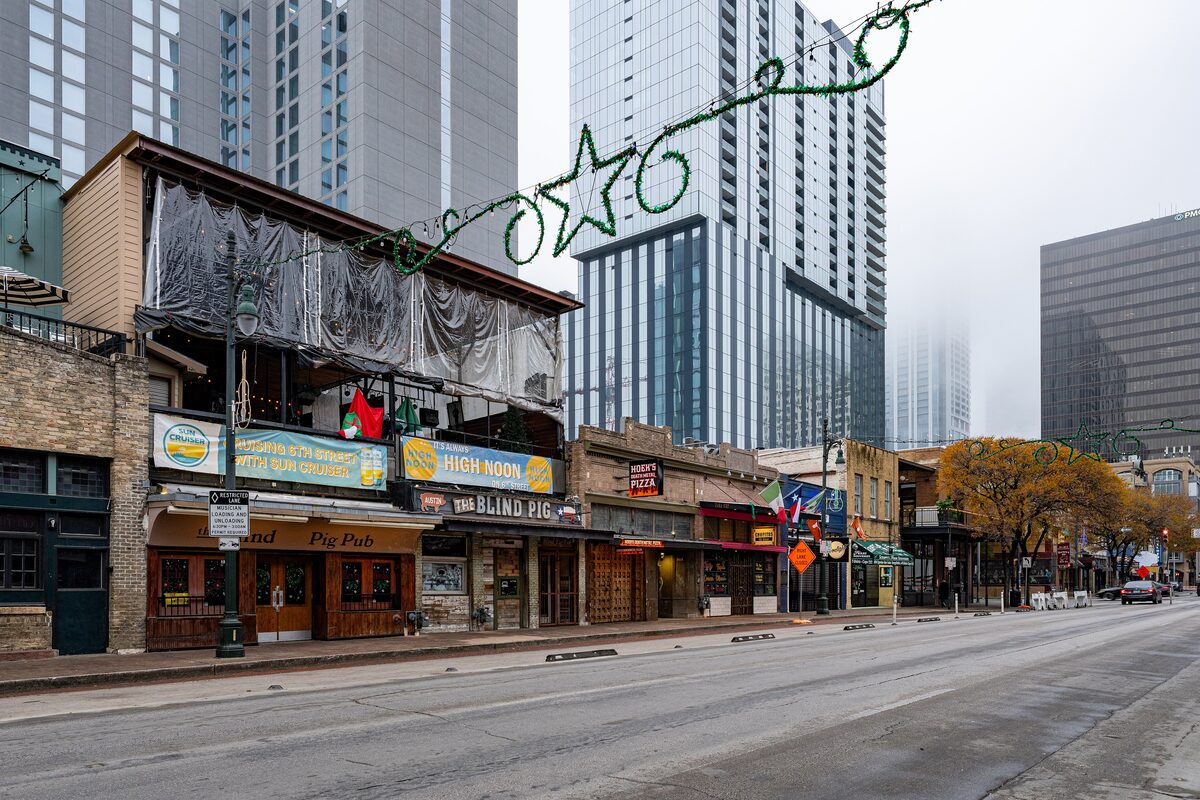 Bars and music venues along Sixth Street in downtown Austin, with high-rise towers behind