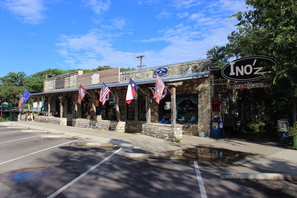 Stone shopfronts with flags and deep porches on the square in Wimberley