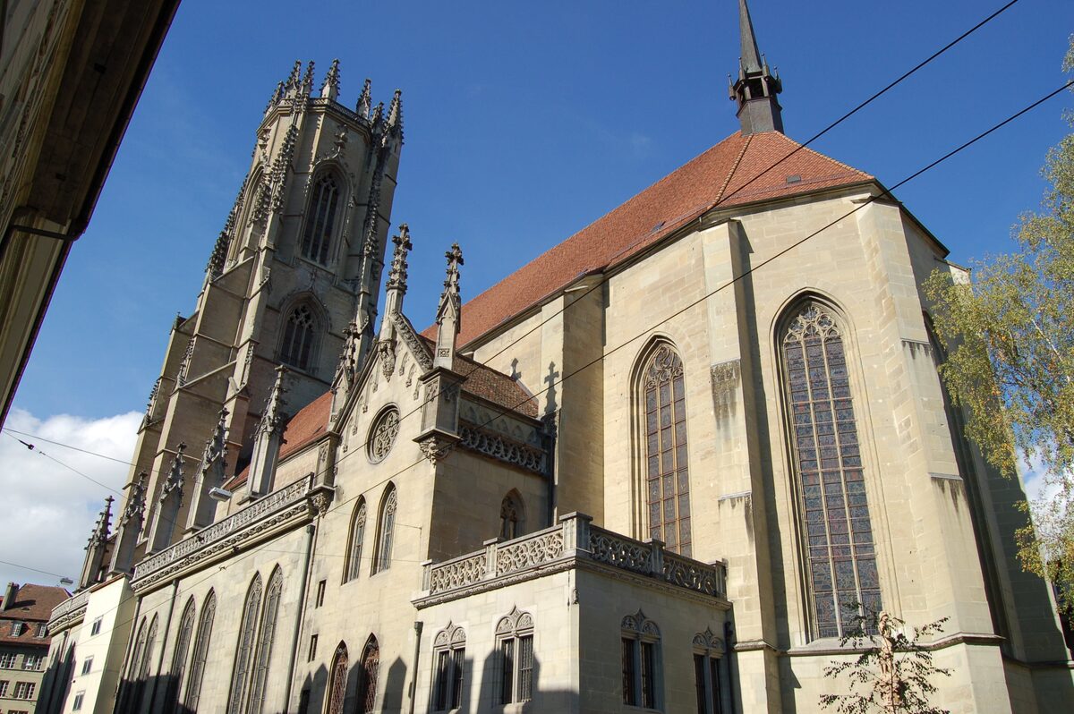 The Gothic Saint Nicholas Cathedral of Fribourg, its tower and pale stone walls under a blue sky