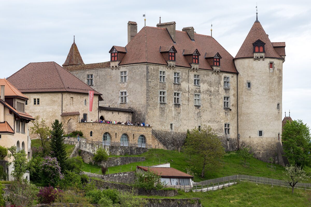 Gruyères Castle with its red roofs and round towers on a grassy hill above the village