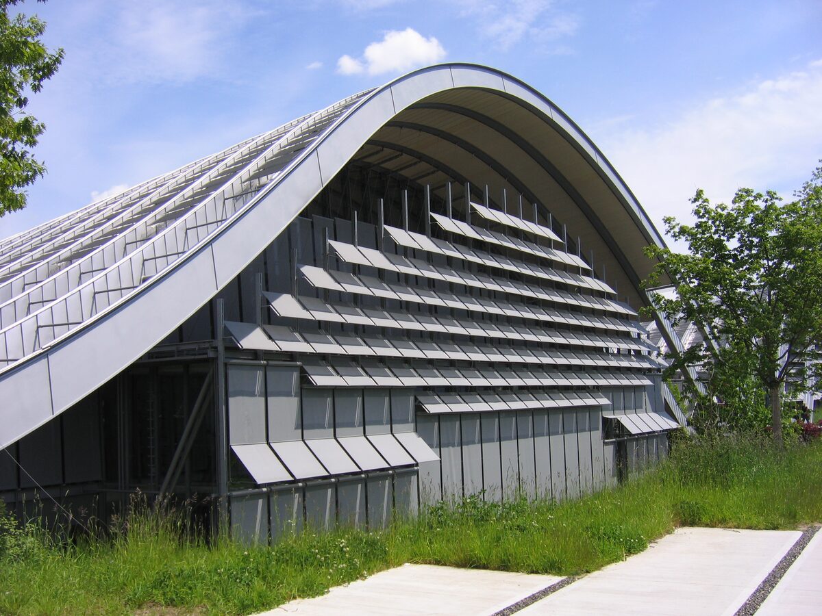 The wave-shaped steel and glass roof of the Zentrum Paul Klee rising over a grassy slope under a blue sky