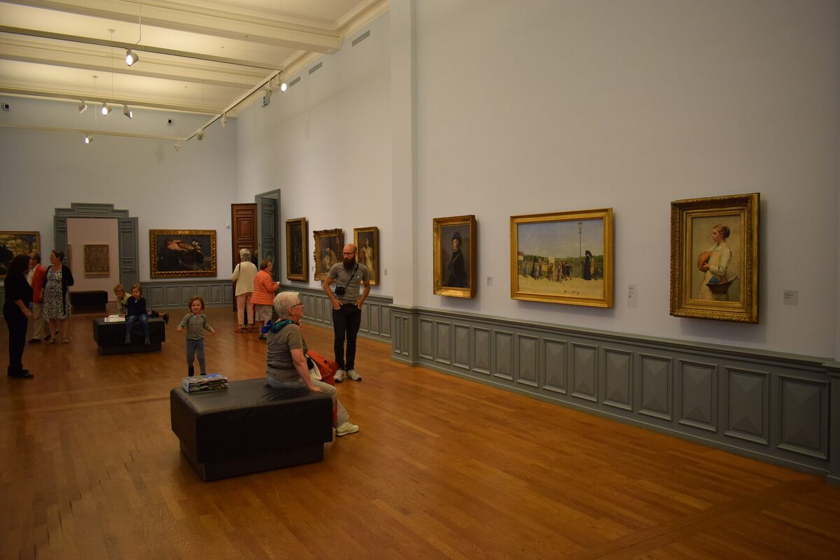 A gallery room in the Kunstmuseum Bern with framed paintings on pale walls and a few visitors
