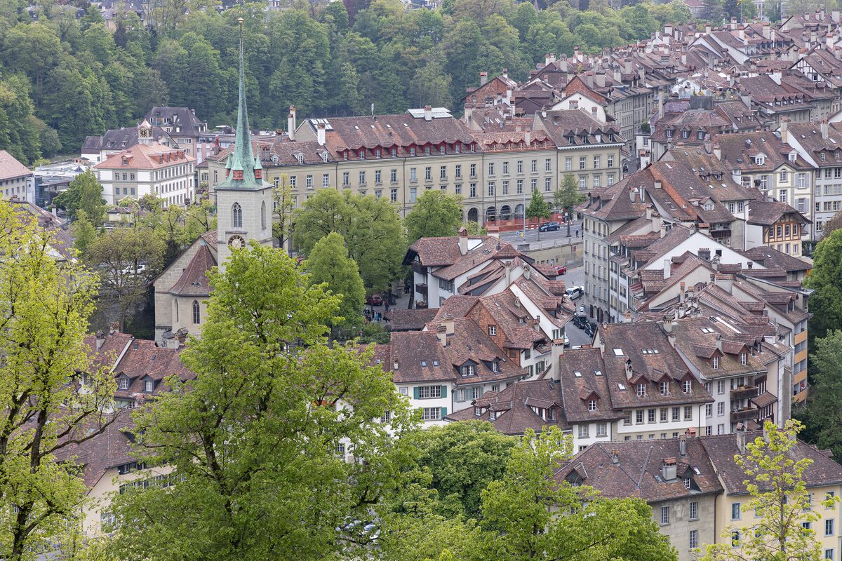 The old town of Bern seen from the Rosengarten, with the Nydegg church spire among red roofs and trees