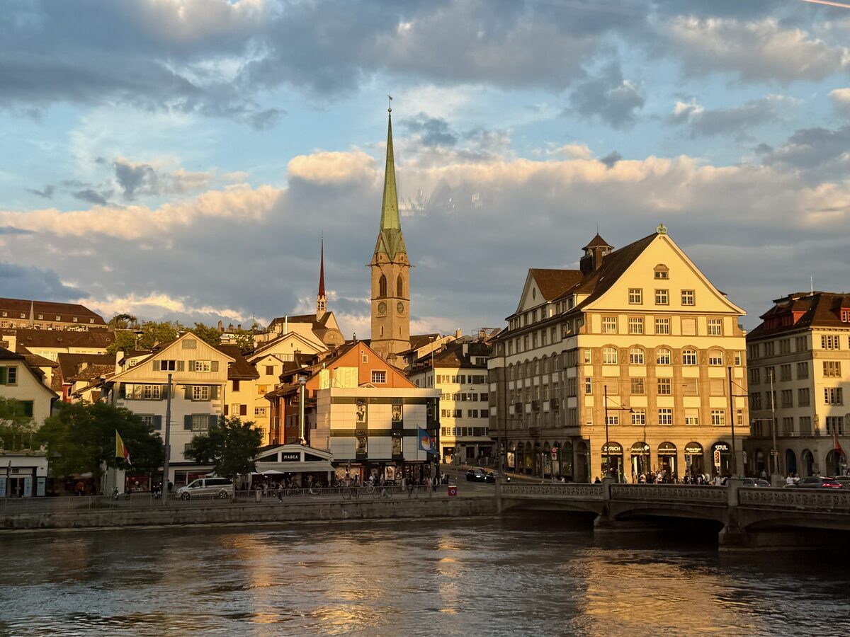 The old town of Zurich along the Limmat river, with a church spire in evening light